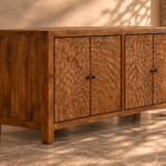 Angled view of the Rosette bar cabinet in a warm brown wood finish, showing four floral-patterned doors, dark round knobs, a smooth left side with visible grain and square legs.