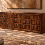 Angled view of the Porticco bar cabinet in a warm brown wood finish, showing panelled doors, dark decorative handles, exposed hinges and a plain right side with visible grain.