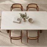 Top view of the OREN dining table with an ivory rectangular tabletop, subtle veining and rounded corners, surrounded by six chairs with cane backs and beige upholstered seats.
