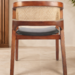 Rear view of the CAFFEINA chair with a warm-finished acacia wood frame, natural cane backrest and black upholstered seat.