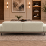 Rear view of the Continentale sofa in ivory Aston 902 upholstery, showing two broad back panels, low arms, a slim brown base and dark legs.