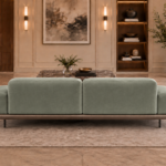 Rear view of the Continentale sofa in sage-green Aston 922 upholstery, with two broad back panels, low arms, a brown base and slim dark legs.