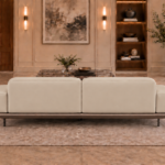Rear view of the Continentale sofa in beige Phantom 104 leatherette, with two broad back panels, low padded arms, a teak finish base and slim dark legs.