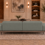Rear view of the Continentale sofa in grey-green Phantom 124 leatherette, with two rounded back panels, low padded arms, a teak finish base and slim dark legs.