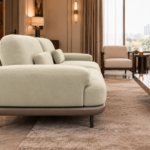 Side view of the Continentale sofa in ivory Aston 902 upholstery, showing a wide padded arm, deep seat, brown base and slim dark legs.