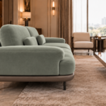Side view of the Continentale sofa in sage-green Aston 922 upholstery, with a wide padded arm, deep seat, brown base and slim dark legs.