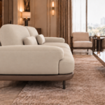Side view of the Continentale sofa in beige Phantom 104 leatherette, with a broad padded arm, deep seat, teak finish base and slim dark legs.
