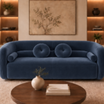 Front view of the Formosa sofa upholstered in deep blue Giza 114 fabric, featuring a continuous curved back, broad seating and matching round and bolster cushions.