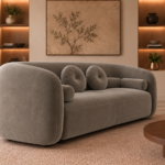 Angled side view of the Formosa sofa upholstered in Giza 109 fabric, showing its continuous curved back, rounded arms and coordinated cushions.