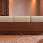 Rear view of the Grand Turismo Dark Wood three-seater sofa, featuring light beige cushions, a broad wooden back panel with visible grain, rounded armrests, curved side supports and tapered legs.