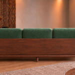 Rear view of the Grand Turismo Dark Wood sofa with three forest green Aston 921 patterned back cushions, a broad wooden back panel, rounded armrests, curved supports and tapered legs.