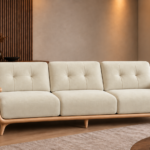 Front view of the Grand Turismo three-seater sofa in ivory Aston 902 fabric, with stitched back cushions, broad wooden armrests, a rounded light wood frame and tapered legs.