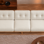 Overhead view of the Grand Turismo three-seater sofa in ivory Phantom 102 leatherette, showing three equal seat cushions, rectangular stitching on the back cushions, broad wooden armrests and a rounded frame.