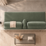 Overhead view of the Solaris sofa in sage green patterned fabric, showing a continuous bench seat, two back cushions, a central wedge bolster, an ivory platform and a round side table.