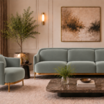 Front view of the Duet three-seater sofa and matching armchair in grey-green Phantom 118 leatherette, with rounded arms, separate seat and back cushions, gold finish base trim and slender legs.