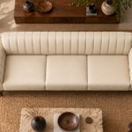 Overhead view of the Venetia sofa in cream leatherette, showing three equal seat cushions, a vertically channelled backrest, rounded channelled arms and gold-finish supports at the front corners.