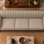 Overhead view of the Venetia sofa in light taupe leatherette, showing three equal seat cushions, a vertically channelled backrest, rounded channelled arms and gold-finish supports at the front corners.